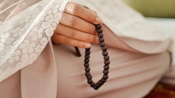 Ilustrasi seorang perempuan membaca zikir pembuka pintu rezeki setelah shalat Subuh