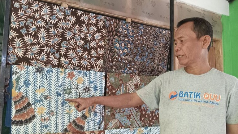 Seorang pekerja menunjukan kain batik dengan pewarna alami di Desa Ciwaringin, Cirebon, Jawa Barat.