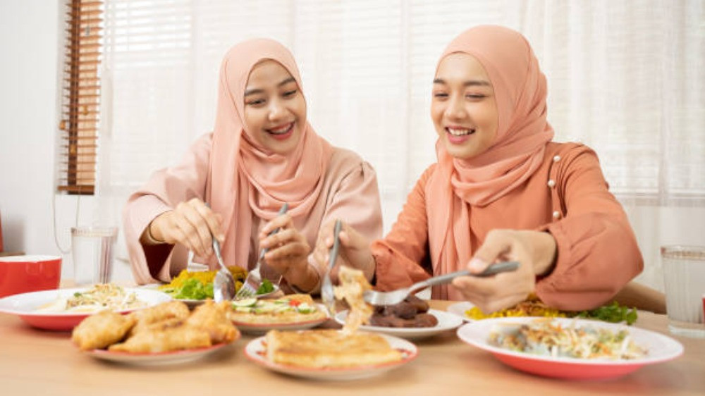 Ilustrasi dua wanita Muslimah makan dan minum setelah imsak sebelum puasa